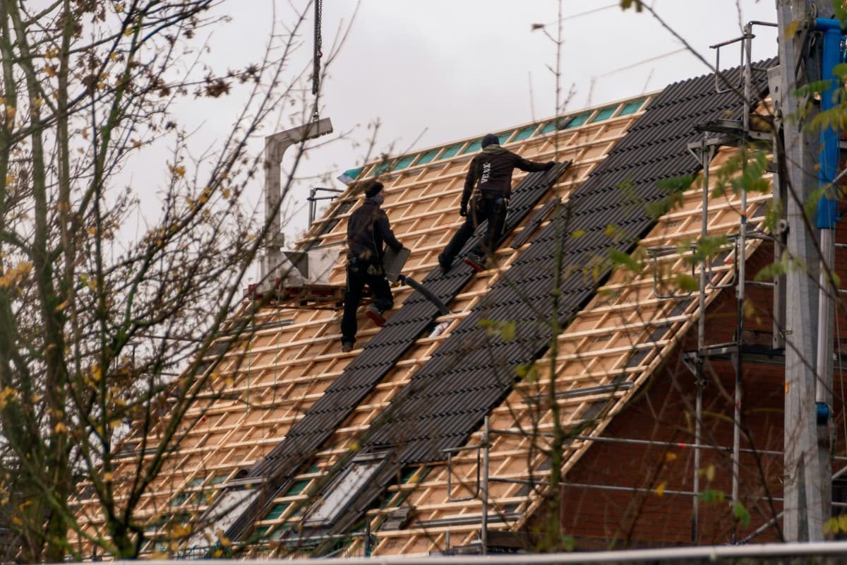 Dakwerker plaatst dakpannen op hellend dak
